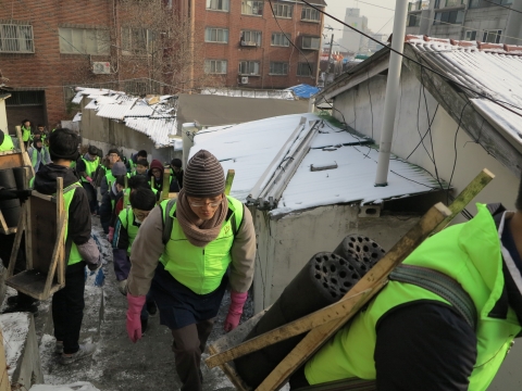 자원봉사자들이 가파른 골목을 지나 대상자집으로 연탄을 배달하고 있다