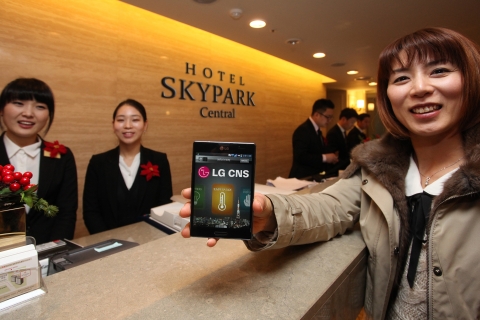 LG CNS(대표 김대훈)와 호텔 스카이파크(대표 최영재)가 스마트폰을 이용한 세계 최초의 ‘스마트 객실 서비스’를 선보였다. 한 일본인 관광객이 호텔 스카이파크 센트럴 명동점 로비에서 객실키와 리모콘 대신 모든 객실 서비스를 이용할 수 있는 스마트폰을 수령하고 있다.