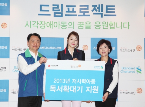 스탠다드차타드은행 정보시스템/운영본부 김수현 부행장(좌측)이 하트하트재단 소이현 홍보대사(가운데)와 신인숙 이사장(우)에게 저시력아동을 위한 독서확대기 전달을 하고 있다.