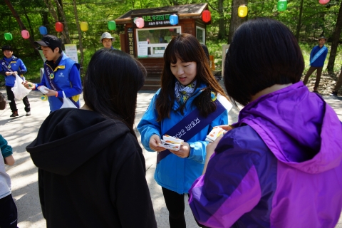 신한아이타스 임직원들이 11일 속리산국립공원에서 직접 제작한 환경보호 캠페인 홍보뱃지와 쓰레기 봉투를 등산객에게 나눠주고 있다.