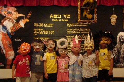 어린이들이 가면무도회 후 유럽의 가면이 전시된 포토존에서 기념포즈를 취하고 있다