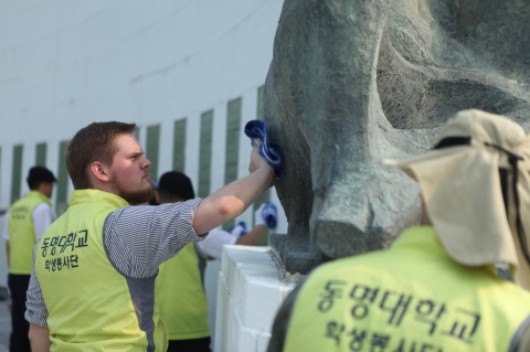 동명대 설동근 총장과 조지아대학에서 온 유학생 등 재학생 66명이 6월 24일 한국전 희생자 넋을 위로하며 유엔기념공원 위령탑을 정성껏 닦고 있다.