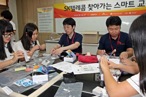 18일 시흥시 대흥중학교에서 실시한 SK텔레콤 찾아가는 스마트교실에서 대흥중학교 학생들이 전문 재능 나눔 봉사자로 참여한 SK텔레콤 구성원의 설명을 들으며 실험에 열중하고 있다.