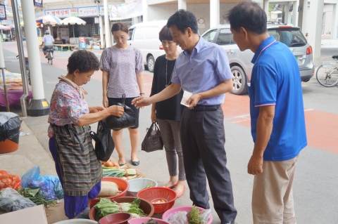 오재양 행정팀장이 시장상인에게서 물건을 사고 있다.