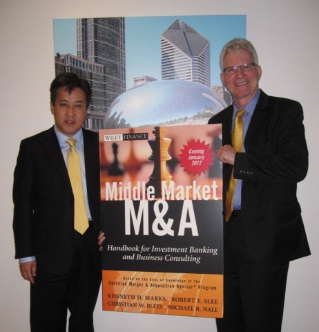 Michael Nall 회장과 이용상 회계사가 Chicago 소재 AM&AA 본부에서 Nall 회장의 저서를 들고 기념촬영을 하고 있다.