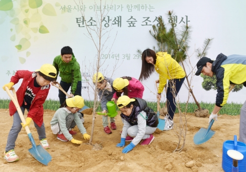 29일 서울시와 이브자리가 주최한 탄소 상쇄 숲 조성 행사에서 참가자 가족들이 나무를 심고 있다