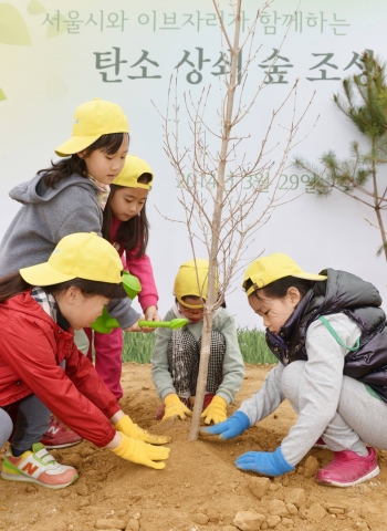 29일 서울시와 이브자리가 주최한 탄소 상쇄 숲 조성 행사에서 참가자 가족들이 나무를 심고 있다