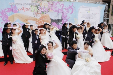 25일 오후 1시부터 한국방송통신대에서 진행된 사랑의 무료 합동결혼식에서 함께 한 14쌍의 부부가 사랑의 표시로 하트를 만들고 있다.