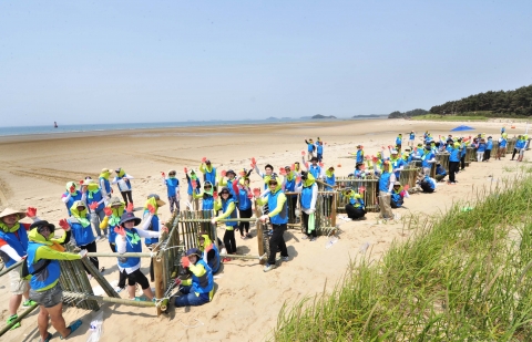 한국암웨이 임직원들이 태안해안국립공원 내 기지포∙상봉 해수욕장에서 해안 방제 펜스를 설치하고 있다.