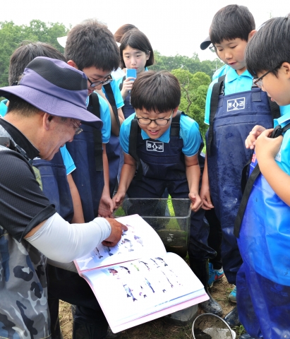 마지초등학교 생각하는 청개구리 과학탐험 대원들이 수집한 물고기 및 생물에 대해 설명을 듣고 있다.