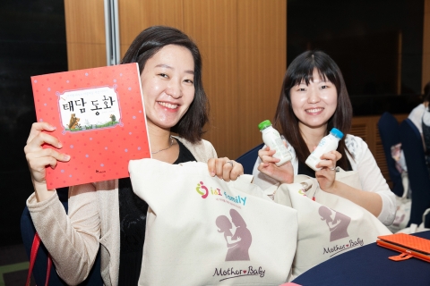 임산부들이 제1회 아이앤아이 패밀리 코칭에서 태담동화, 우유, 무릎 담요, 아기기저귀 등이 담긴 선물을 받고 즐거워하고 있다.