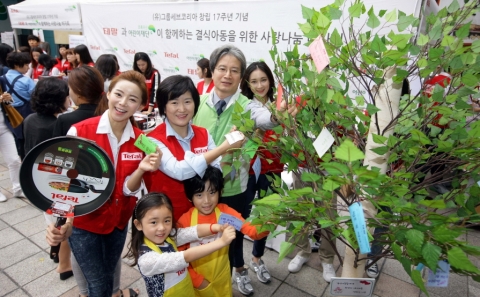 9월 18일 무교동 어린이재단 본부 앞 광장에서 진행된 테팔, 사랑나눔 바자회에서 팽경인 테팔 대표 및 직원들과 이충로 초록우산 어린이 재단 본부장이 결식아동들을 위한 응원의 메시지를 희망트리에 달고 있다.
