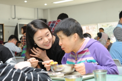 설을 맞아 봉사활동에 나선 한국교직원공제회 직원이 시각중복 장애인 공동체 여주 라파엘의 집을 방문해 일일 도우미 활동을 펼치며 몸이 불편한 시각중복 장애인의 식사를 돕고 있다.