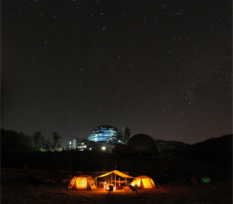 starry night. 야영캠프 참가자들이 어두운 밤하늘에 펼쳐진 별빛 아래에서 야영을 즐기고 있다. 국립고흥청소년우주체험센터는 우주과학을 주제로 별밤야영캠프 개최하고 있다
