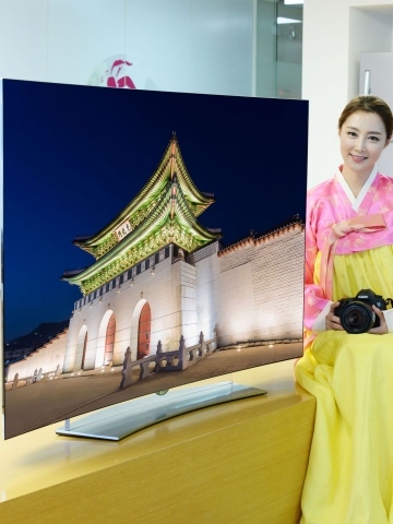 모델이 65형 울트라 올레드 TV와 함께 포즈를 취하고 있다. TV에 나오고 있는 화면은 경복궁 사진.