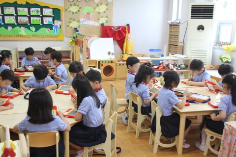 어린이집에서 유아들이 스마트기기를 활용해 교육받는 장면