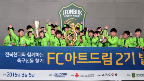 FC아트드림 2기 참여 아동들이 전북현대모터스FC의 과거 우승컵을 들고 기념 촬영하고 있다