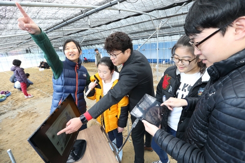 KT IT 서포터즈와 함께 임자초등학교 어린이들이 스마트팜에서 스마트기기를 연결해 농작물 관리법을 학습하는 모습이다