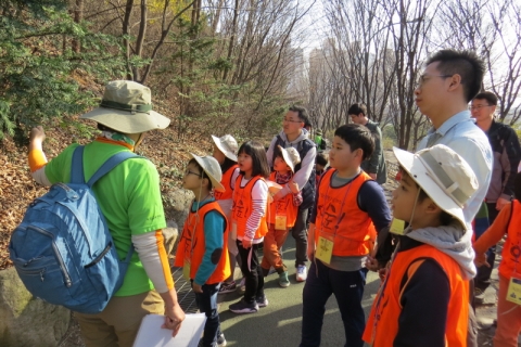 봉사활동에 참가한 한화생명 임직원이 아이들과 함께 나무에 대한 설명을 듣고 있다