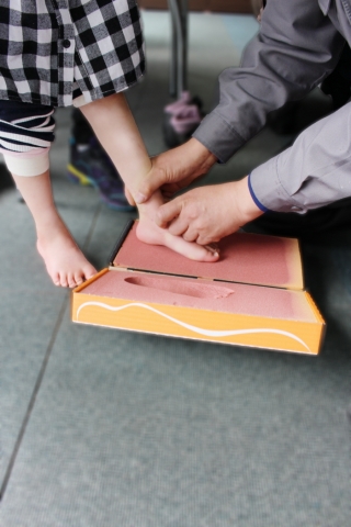 아이의 맞춤 신발 제작을 위하여 발 본을 뜨고 있다