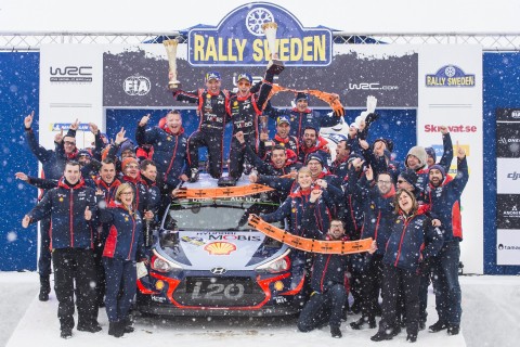 현대 월드랠리팀 선수 및 관계자들이 2018 WRC 스웨덴 랠리 시상대에서 기념 사진을 촬영하고 있다. 신형 i20 랠리카 위에서 니콜라스 질술(왼쪽)과 티에리 누빌이 우승컵을 들고 환호하고 있다