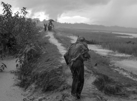 진흙탕이 된 길을 따라 아이를 안고 방글라데시로 탈출하고 있는 한 로힝야 여성