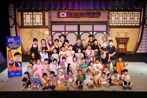 공연이 끝난 뒤 배우들과 어린이들이 무대 위에서 함께 기념촬영을 하고 있다