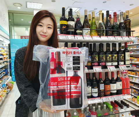 GS25에서 모델이 와인25플러스 서비스 상품을 들고 포즈를 취하고 있다