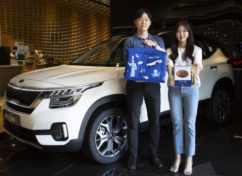 GS리테일의 밀키트 브랜드 심플리쿡을 들고 기아자동차의 소형 SUV 셀토스 앞에서 포즈를 취하고 있다