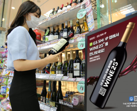 GS25에서 모델이 와인을 살펴보고 있다