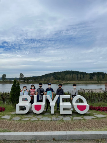 어린이들이 BUYEO(부여) 표지 설치물 앞에서 포즈를 잡고 있다