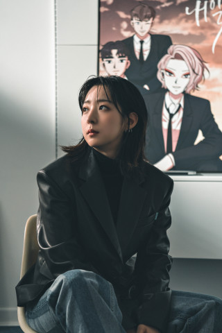 웹툰 내일 포스터 앞에 앉아있는 라마 작가