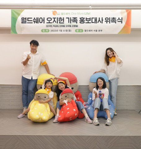 오지헌 가족이 월드쉐어의 마스코트 코니돌 인형과 함께 기념 촬영을 하고 있다