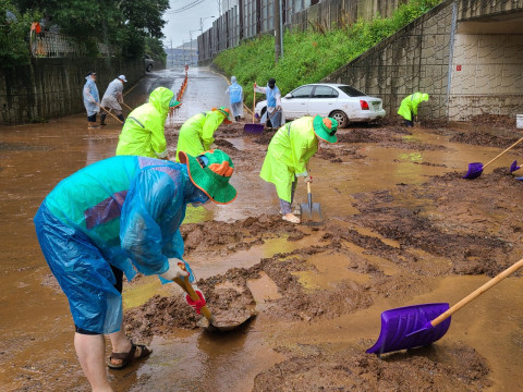 자원봉사자가 도로에 유출된 토사를 제거하고 있다
