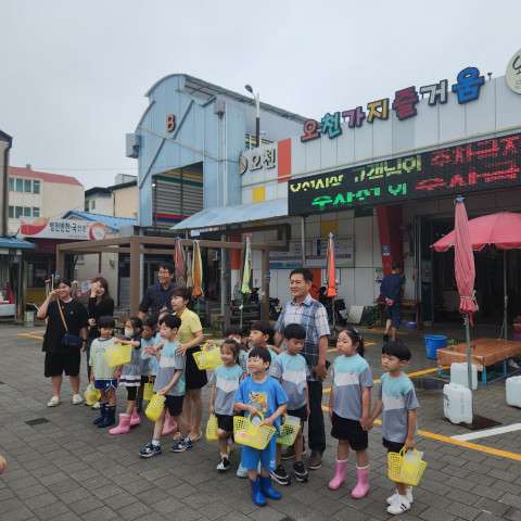 오천시장 앞에서 오천초교 병설유치원 어린이와 안병한 오천시장 상인회장, 이승호 오천초등학교 교장선생님이 기념 촬영을 하고 있다