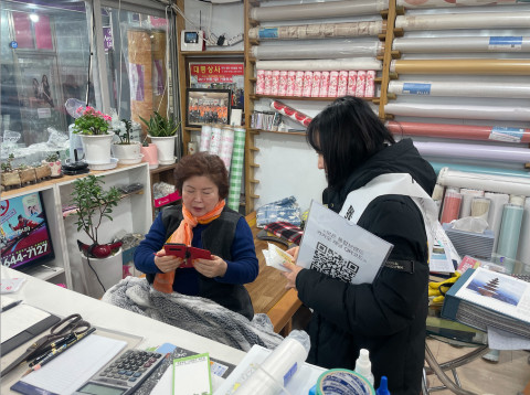결초보은상권활성화사업추진단 관계자가 ‘찾아가는 카카오톡 채널 활성화 프로그램’을 통해 카카오톡이 익숙하지 않은 상권 어르신들에게 채널 추가를 돕고 있다