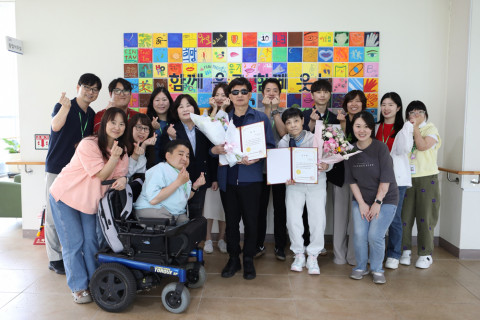 ‘전국 장애인 감성시 공모전’ 수상자 배경옥, 김진수 씨와 한마음복지관 직원들이 수상을 축하하며 기념 사진을 찍고 있다