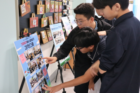 기적스쿨 전시 판넬을 살펴보는 청소년들