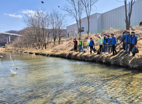 양지천 환경 정화 봉사활동에 참여한 테스 임직원들이 양지천에 EM 흙공을 던지고 있다