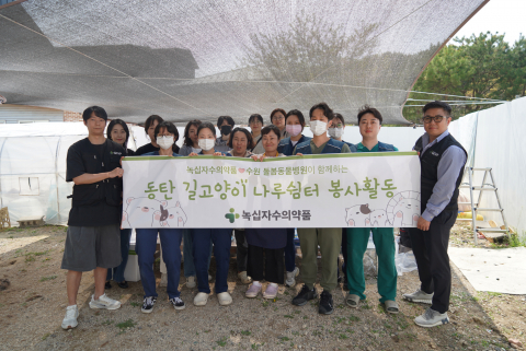 돌봄동물병원 소속 수의사와 직원, 녹십자수의약품 가치그린봉사단원이 동탄 길고양이 나루쉼터에서 봉사활동을 하고 단체사진을 찍고 있다