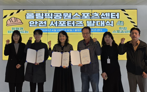 올림픽공원스포츠센터 안전 서포터즈와 센터 임직원이 디지털 현수막을 배경으로 단체 사진을 촬영하고 있다