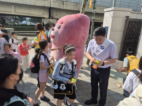 등굣길 교통안전 캠페인 현장에서 신한은행 등 참가 기관 관계자들과 마스코트 인형이 등교하는 서울당서초등학교 어린이들에게 홍보 물품을 나눠주며 인사하고 있다