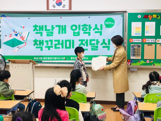 화성시문화재단 전미경 도서관장이 2020년 동탄중앙초등학교 1학년 입학생에게 책꾸러미를 전달하고 있다
