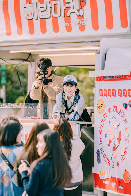 인플루언서 히밥이 부산 광안리에서 진행된 ‘히밥마켓’ 팝업 이벤트에서 시민들에게 음식을 건네주고 있다