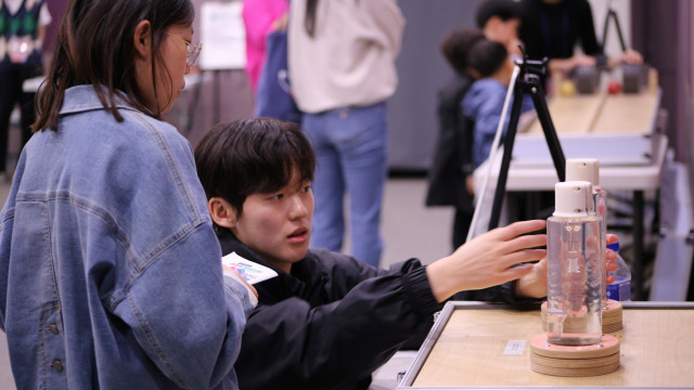 한 청소년이 과학 전시물에 대한 설명을 듣고 있다