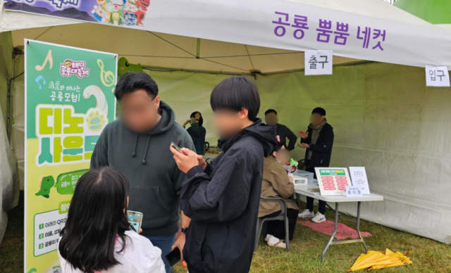 어린이와 가족 관람객들이 QR코드를 스캔해 AI가 만들어주는 나만의 공룡송을 체험하고 있다
