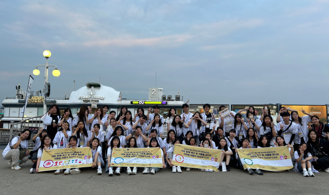불꽃크루즈 체험 전, 한강 유람선 선착장에서. 청소년들이 야경을 배경으로 단체 사진을 촬영하며 역사문화교류캠프의 추억을 기록하고 있다