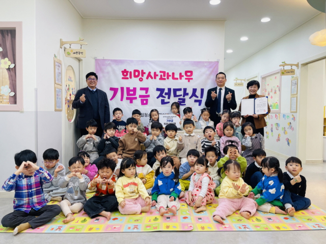 구립청소년회관어린이집이 원아들과 함께 희망사과나무 기부금 전달식을 진행한 후 기념 촬영을 하고 있다