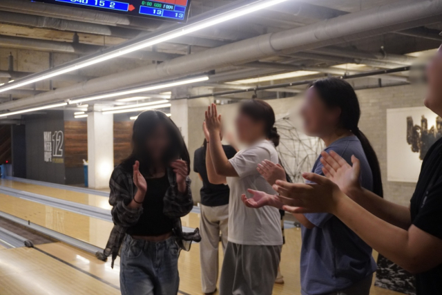 유스톡 스쿨 방학 모델 참여 청소년들이 볼링 활동 중 스트라이크를 친 친구를 박수로 축하하며 서로 격려하고 있다