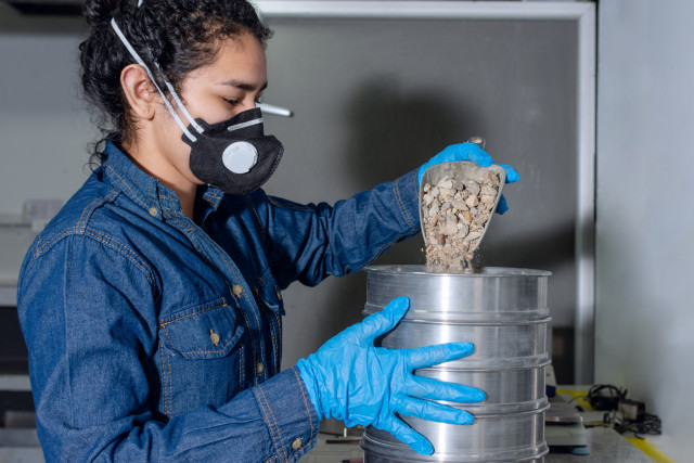 A lab technician is pictured conducting a particle size distribution test.